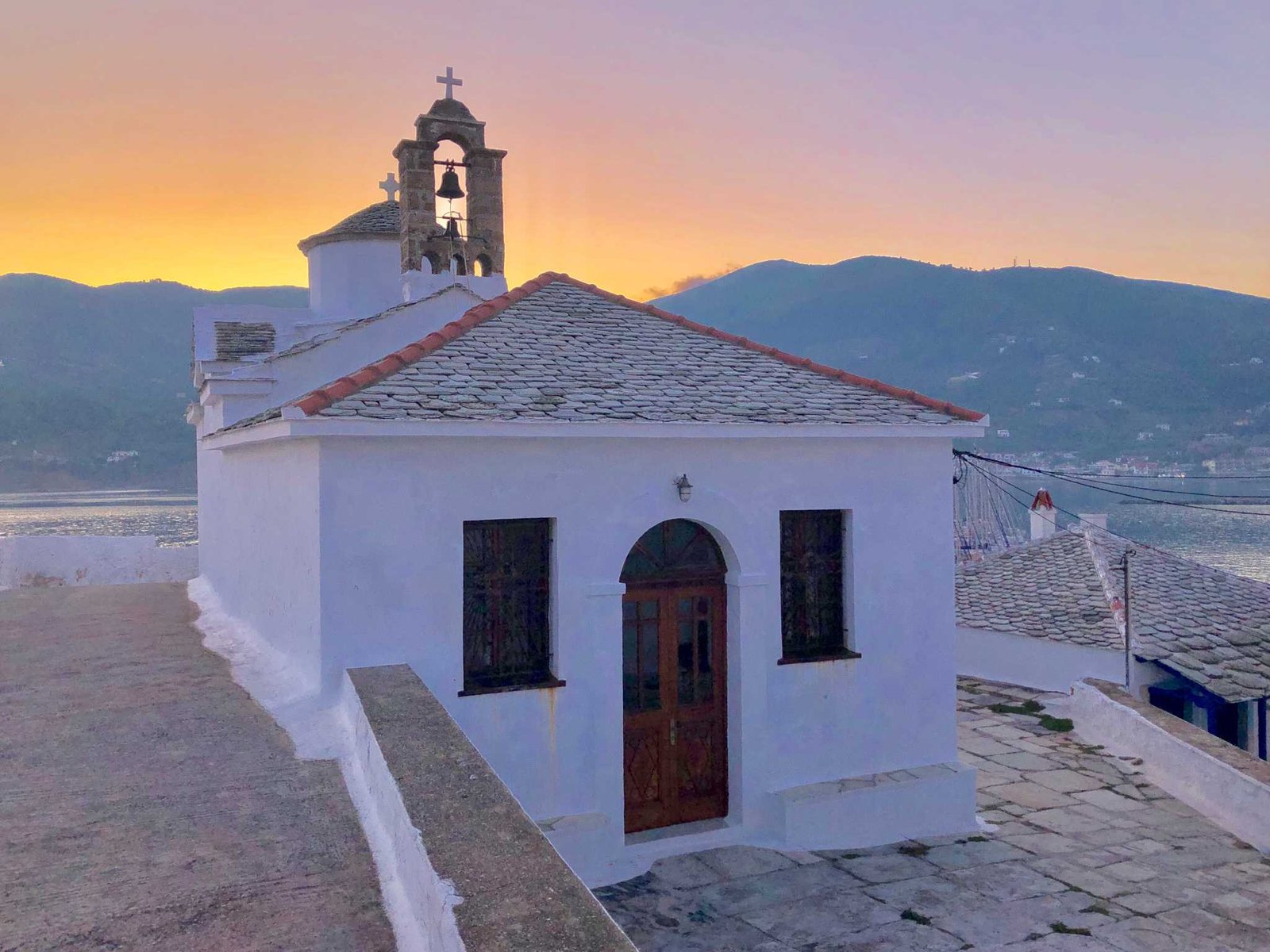 Small whitewashed chapel with bell tower at sunset